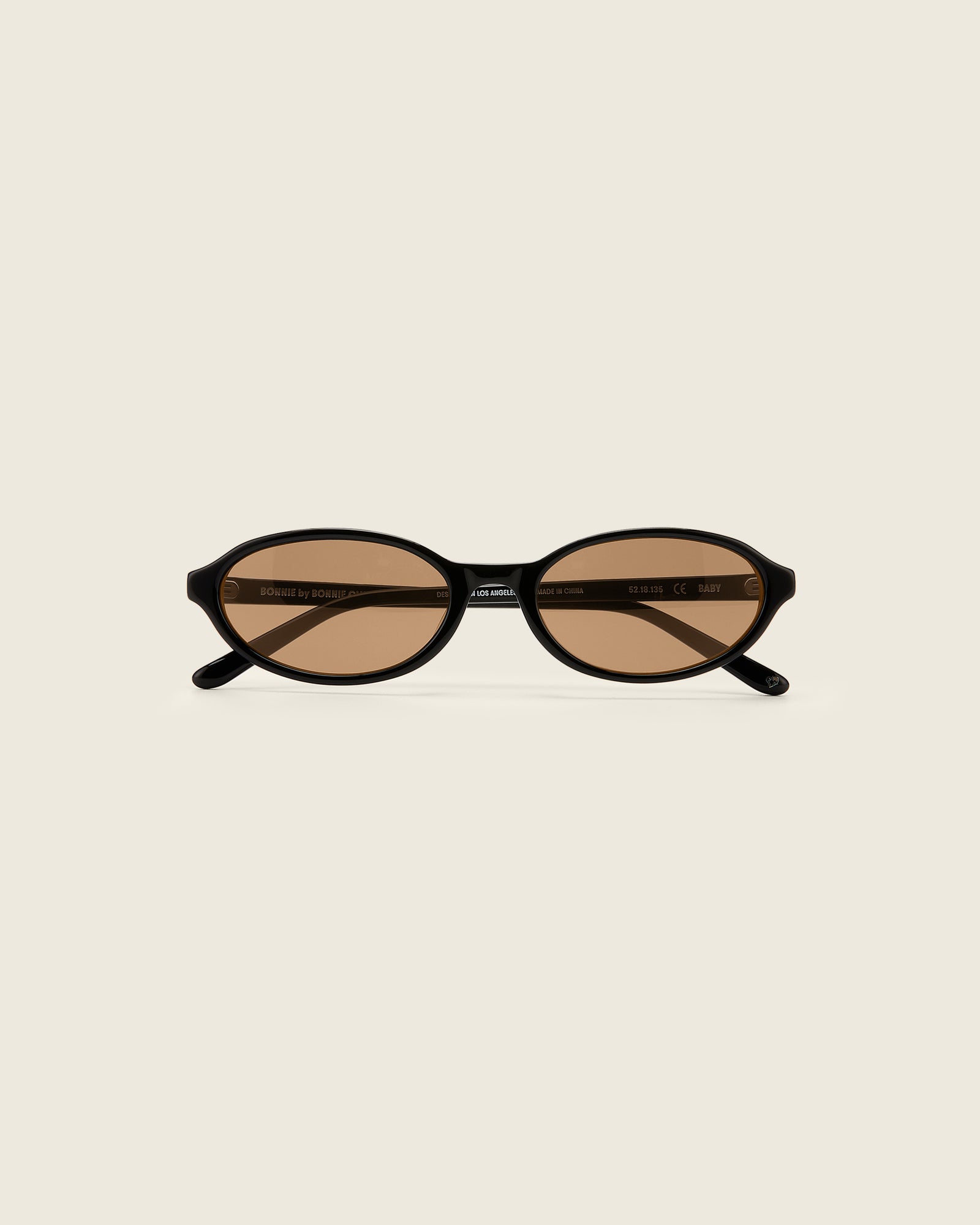 Bonnie Clyde Baby oval sunglasses in black acetate with brown lenses and double heart detailing on the arms, front view